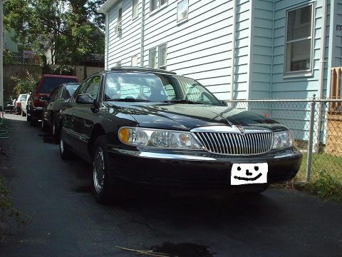 1997 Ford Crown Victoria - A black Lincoln Continental is parked in a driveway with other vehicles behind it.