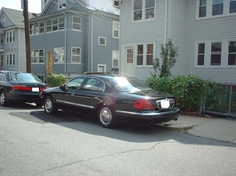 1997 Ford Crown Victoria - A black 1997 Ford Crown Victoria is parked on a residential street next to another car.