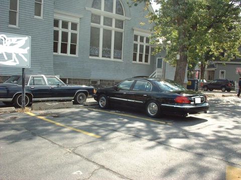1997 Ford Crown Victoria - Rear view of a black sedan, likely a 1995 Lincoln Town Car, parked next to another car.