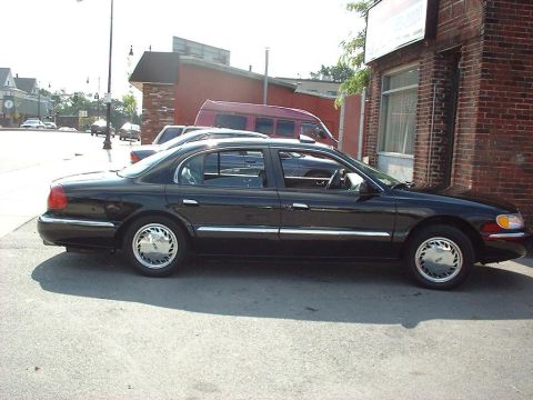 1997 Ford Crown Victoria - Black Lincoln Continental parked curbside, with a red van and other vehicles visible in the background.