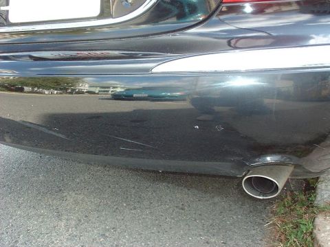 1997 Ford Crown Victoria - Close-up of a car's rear bumper and exhaust pipe, showing scuff marks and chrome trim.