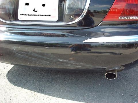 1997 Ford Crown Victoria - Rear view of a black car showing the bumper, chrome accents, and exhaust pipe. The word 'CONTINENTAL' is visible on the taillight assembly.