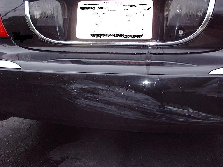 Black car bumper with significant scuffing and damage on the right side