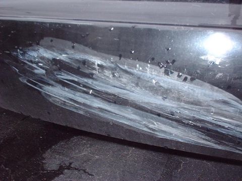 1997 Ford Crown Victoria - This photo shows a damaged black car bumper with significant white paint transfer and scratches.