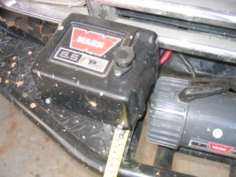 1986 Ford F-150 - Close-up of a Warn 9.5P winch attached to a vehicle's front end, showing mud splatters.