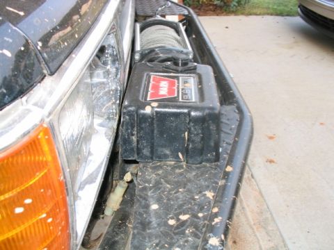 1986 Ford F-150 - A Warn winch is installed on the front of a vehicle, with mud splatters visible on the bumper and body.