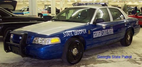2001 Ford Crown Victoria - A 2001 Ford Crown Victoria police car is parked indoors with other vehicles.