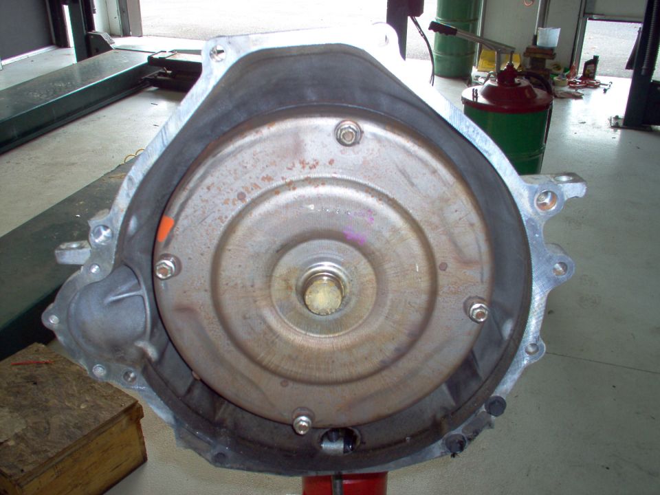 Automatic transmission bellhousing with rusty torque converter on a stand in an auto shop