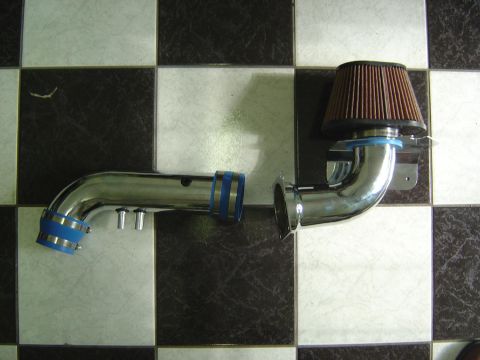 1993 Ford Bronco - Chrome intake pipe with blue couplers and a brown air filter, shown on a checkered floor.