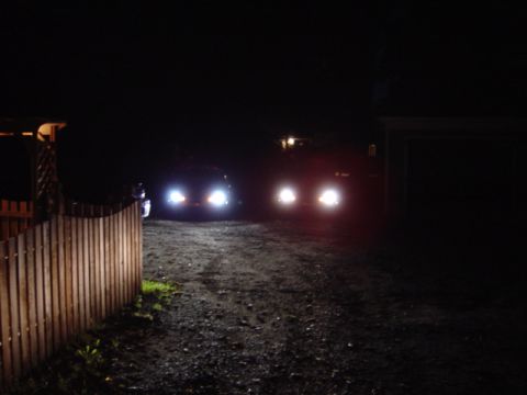 1998 Ford Taurus - Two vehicles approach on a dark, unpaved road, their headlights illuminating the scene.