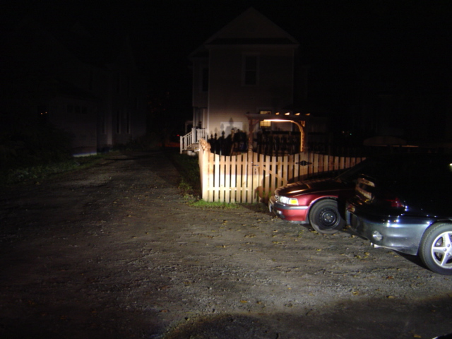 Two cars parked at night, one red and one dark colored