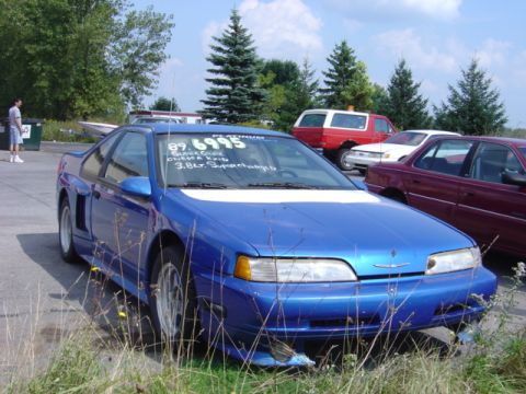 1998 Ford Taurus - A blue 1989 coupe, possibly a Thunderbird, is parked outdoors with other vehicles.