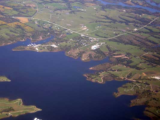 Aerial view of a large blue lake with a town and green hills in the background