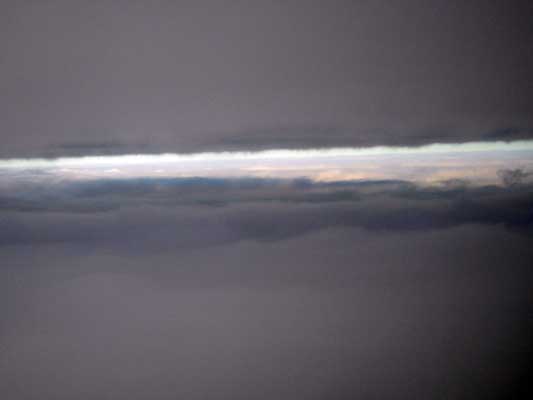 Hazy view of a band of clouds and gray overcast sky, possibly from an aircraft window