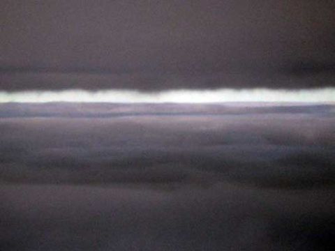 1995 Ford Bronco - A dramatic sky scene with dark, layered clouds illuminated by a bright horizontal band of light.