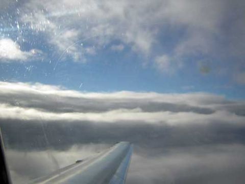 1995 Ford Bronco - Looking out the window at the clouds and airplane wing during flight.