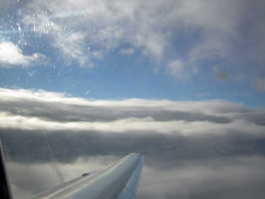 View from airplane window showing wing and clouds below