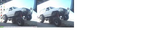1988 Ford Bronco - Two heavily modified white SUVs with oversized tires are positioned on an incline.