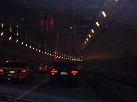 1995 Ford Bronco - Vehicles drive through a tunnel illuminated by rows of lights.
