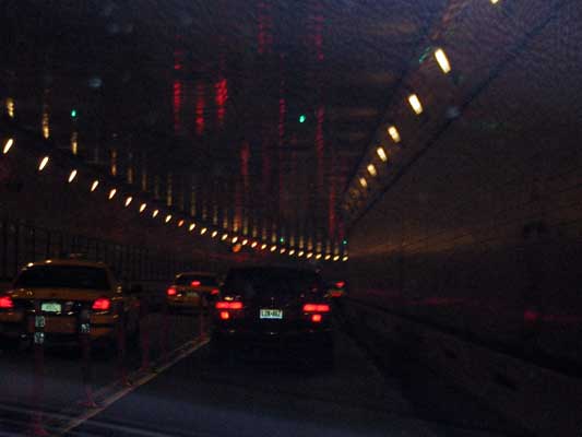 Yellow taxi and black car in tunnel at night