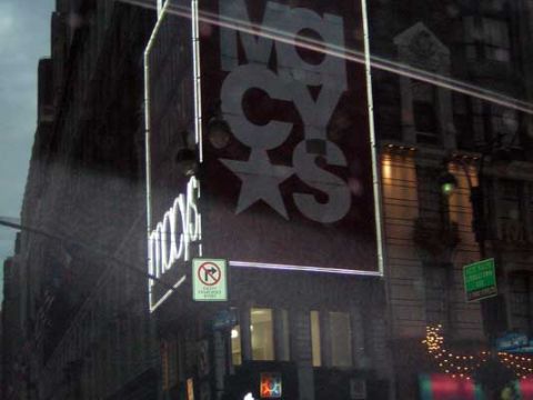 1995 Ford Bronco - A large Macy's sign is visible on a building facade with street signs and lights.