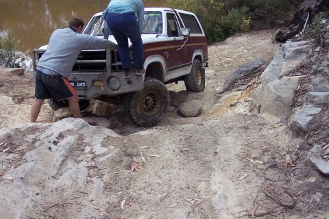 1982 Ford Bronco - 1982 Ford Bronco tackles a difficult off-road obstacle with help from passengers.