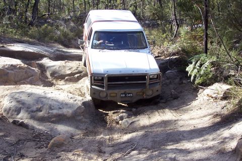 1982 Ford Bronco - This vehicle is navigating a challenging rocky terrain on a wooded trail.
