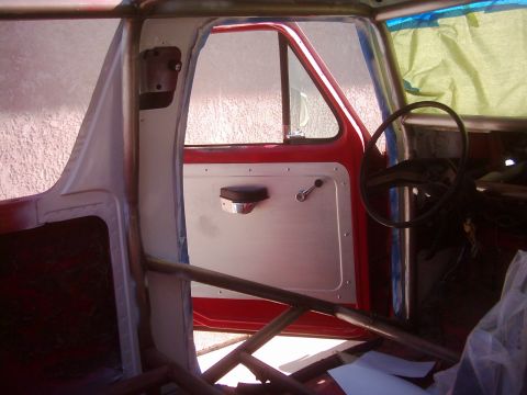 1978 Ford Bronco - The interior of a red vehicle shows a custom door panel and a prominent roll cage, suggesting modifications for racing or off-roading.