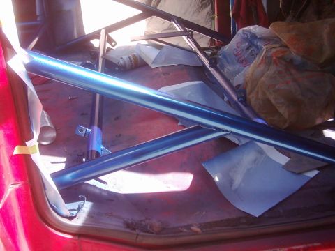 1978 Ford Bronco - Roll cage tubing, painted blue, is visible inside a vehicle with other items in the background.