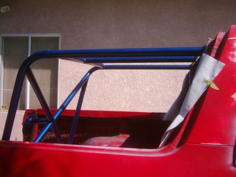 1978 Ford Bronco - A blue roll cage is installed in the bed of a red pickup truck, with some of the interior visible.