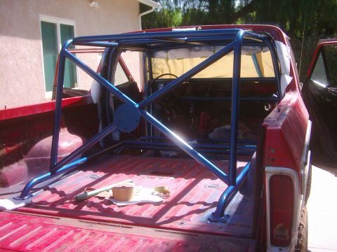 1978 Ford Bronco - Installing a blue roll cage in the bed of a red 1978 Ford Bronco.