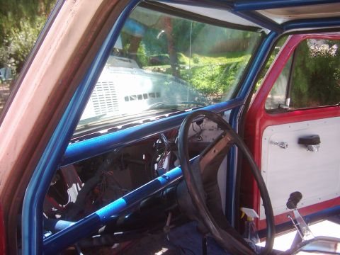 1978 Ford Bronco - The interior of a 1978 Ford Bronco shows a blue roll cage and a white door panel.