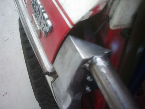 1978 Ford Bronco - Fabricated steel bracket welded to a tube and bolted to a red-and-white vehicle body near the tire.