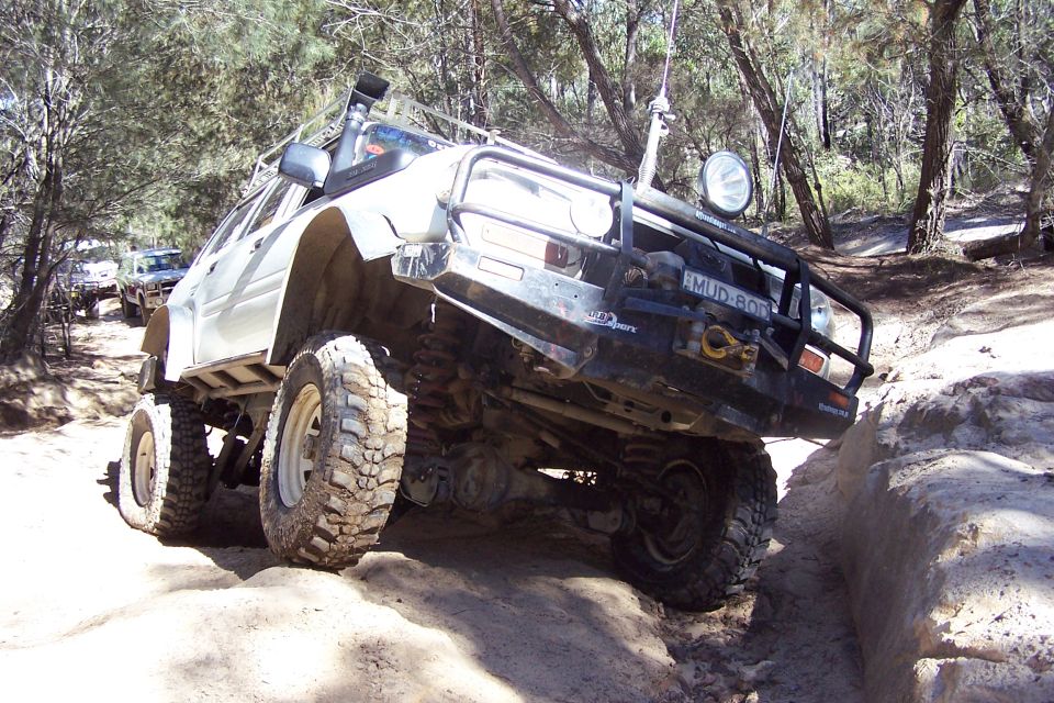 Off-road vehicle with snorkel and bull bar climbing over rocks on a dirt trail