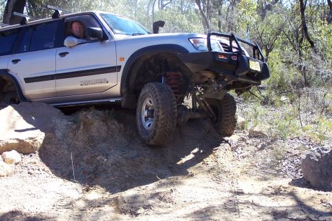 1982 Ford Bronco - This silver SUV is equipped for off-road adventures, tackling a challenging dirt incline with its snorkel and bull bar visible.