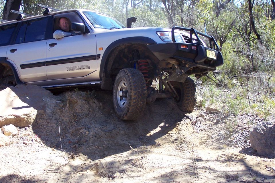 Silver SUV with snorkel and bull bar navigating rough terrain