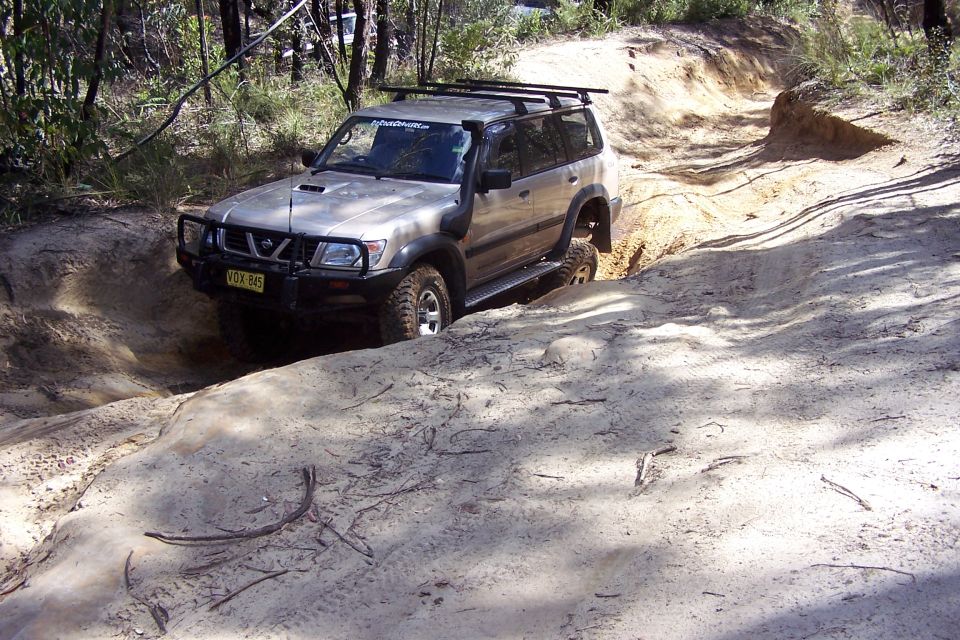 Nissan Patrol navigating a steep dirt trail with a snorkel and roof rack