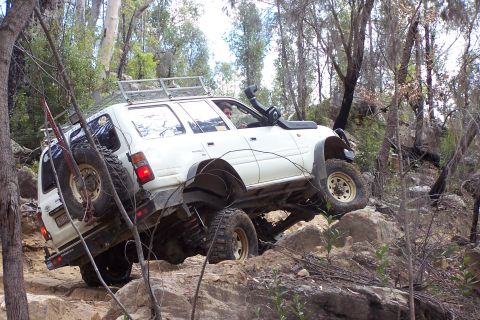 1982 Ford Bronco - This SUV is tackling a challenging off-road course with steep inclines and large rocks.