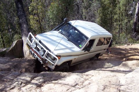 1982 Ford Bronco - Off-road SUV navigating a challenging rocky terrain with steep inclines and drops.