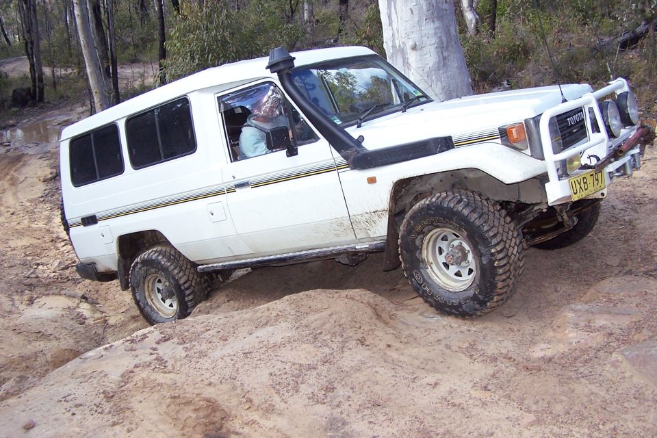 White Toyota Land Cruiser J70 off-roading on a dirt track, front-right 3/4 view