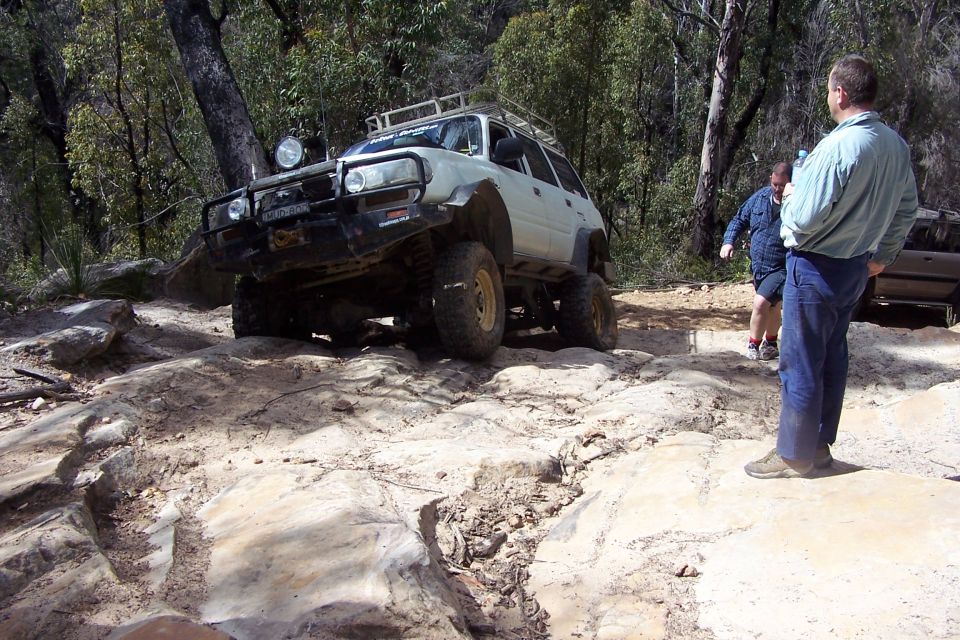 White off-road SUV with roof rack and bull bar on rocky trail