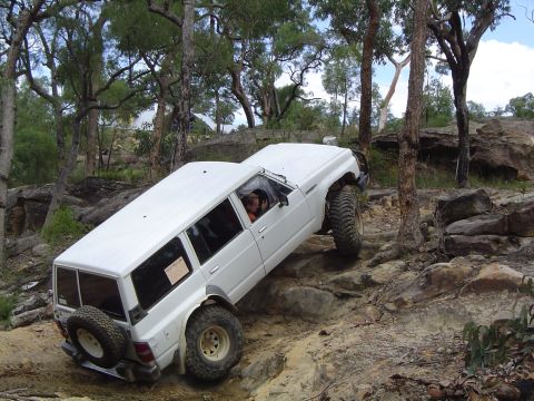 1982 Ford Bronco - White SUV tackling a challenging off-road course on a sunny day.