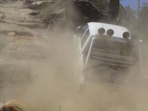 1982 Ford Bronco - Off-road vehicle navigates a dusty, rocky trail.