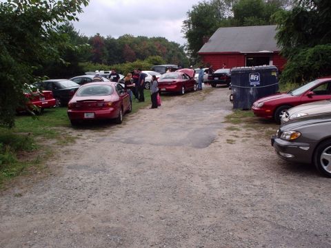1998 Ford Taurus - Several cars are gathered in a gravel lot, with a red building in the background.