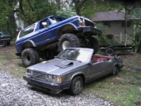 1979 Ford Bronco - A lifted blue 1978 Ford Bronco is parked on top of a silver convertible. A trailer is visible behind them.