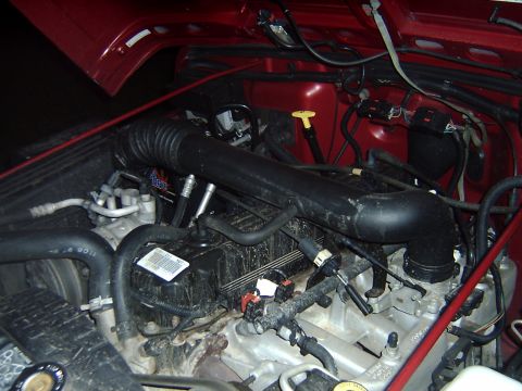 1998 Jeep TJ - Engine bay of a 1998 Jeep TJ, showing the engine components and red exterior paint.