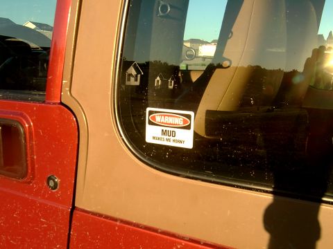1998 Jeep TJ - A sticker on a red Jeep door reads "WARNING MUD MAKES ME HORNY".