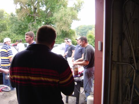 1998 Ford Taurus - A group of men are socializing outdoors near a garage with vehicles present.