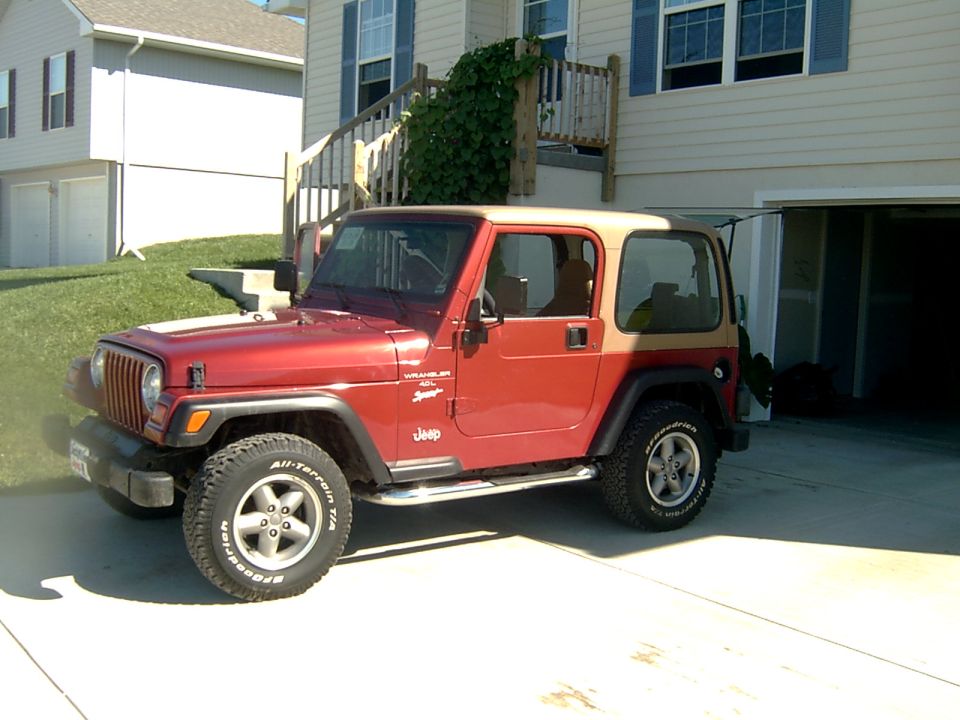 Red Jeep Wrangler with tan hardtop and BFGoodrich A/T tires parked in a driveway