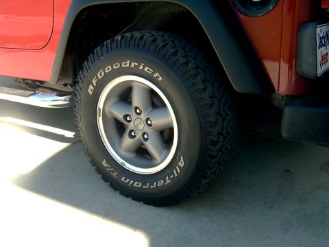 1998 Jeep TJ - A red Jeep Wrangler's side profile is visible, focusing on the tire and wheel assembly.